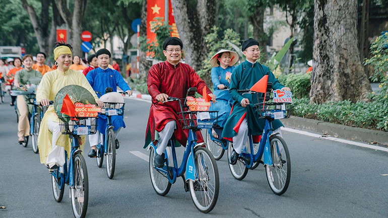 Người dân Thủ đô trong tà áo dài truyền thống đạp xe diễu hành trên đường phố Hà Nội tạo khung cảnh đẹp trong những ngày tháng Tám lịch sử. (Ảnh CHÍ DŨNG)