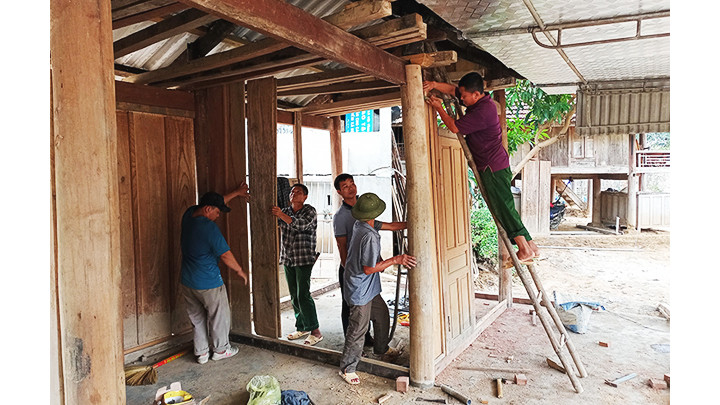 Bà con dân bản và người thân giúp gia đình ông Kha Văn Quang dựng lại nhà.