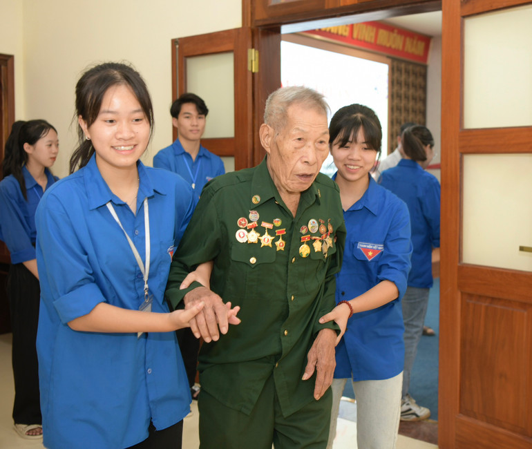 Một cựu chiến binh được các thanh niên tình nguyện đưa đến tham dự lễ gặp mặt.