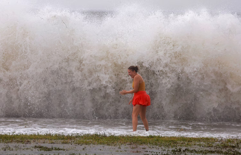 Một người phụ nữ đứng ở vùng nước nông. Phía sau là những con sóng dữ dội do bão Helene gây ra tại thành phố St. Petersburg. (Ảnh: ABC News)