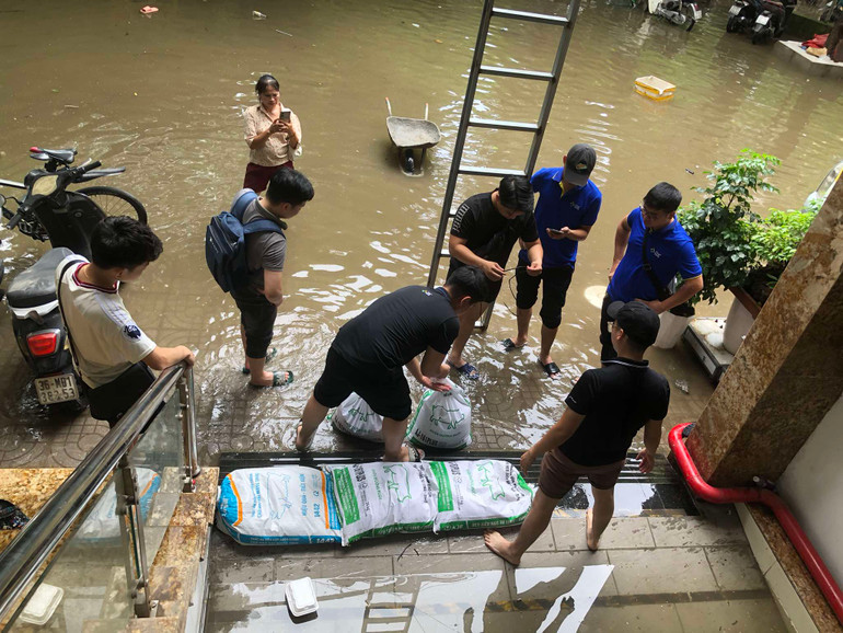Nước từ bên ngoài đường dâng cao tràn vào cửa hầm. Để hạn chế tình trạng trên, những người sống tại chung cư mini đã phải dùng cát đựng trong các bao tải để chặn lại trước cửa.