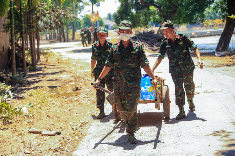 Các chiến sĩ bộ đội vận chuyển nước sạch tới các hộ dân tại xã Nam Phương Tiến.