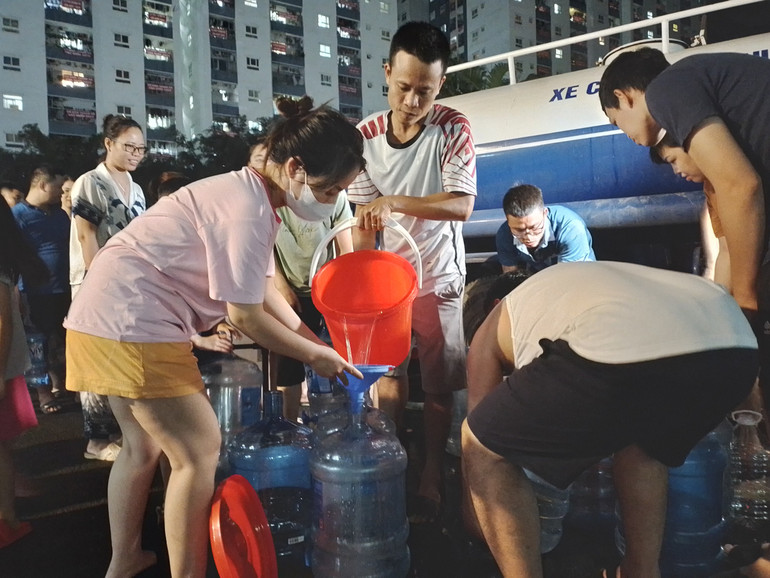 Người dân hứng từng xô nước sạch về sử dụng. (Ảnh chụp lúc 21 giờ tối 24/10)