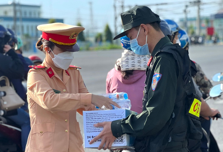 Chiến sĩ Cảnh sát giao thông Đồng Nai phát nước suối cho người dân trên quốc lộ 51.