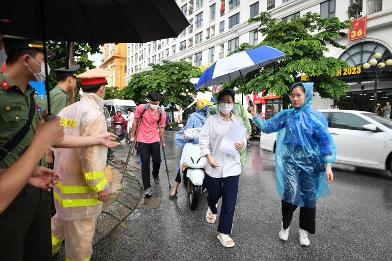 Các thí sinh đội mưa tới điểm thi Trường trung học phổ thông Nguyễn Trãi (Hà Nội). (Ảnh: Thành Đạt)