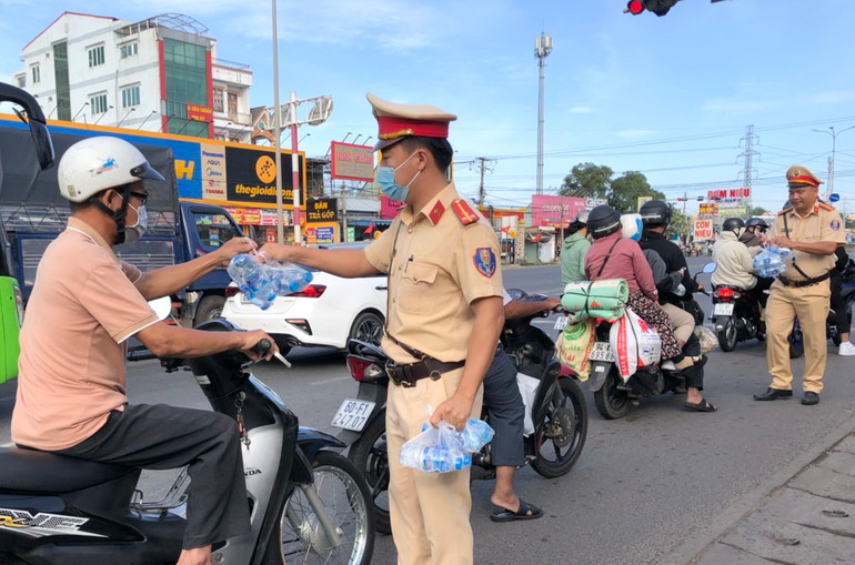 Chiến sĩ Cảnh sát giao thông Đồng Nai phát nước suối cho người dân trên quốc lộ 51.