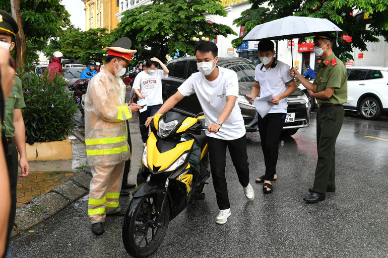 Lực lượng an ninh làm việc tại điểm thi Trường trung học phổ thông Nguyễn Trãi che ô cho các thí sinh. (Ảnh: Thành Đạt)