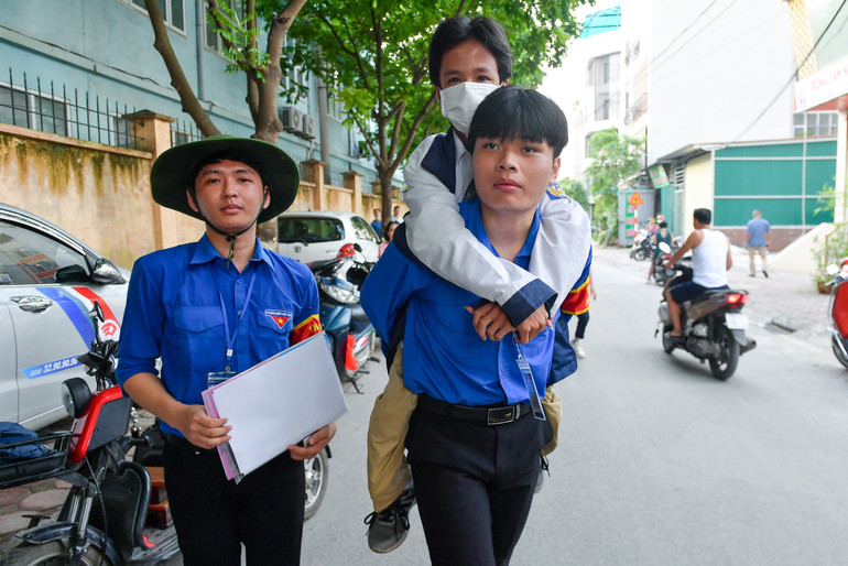 Thí sinh Nguyễn Hữu Chính được các sinh viên tình nguyện cõng vào phòng thi. (Ảnh: Thành Đạt)