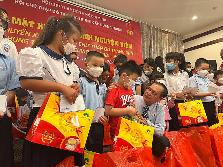 Chủ tịch Hội Chữ thập đỏ Thành phố Hồ Chí Minh Trần Trường Sơn (người ngồi) tặng quà cho các bé.