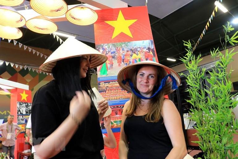 Những cô gái Nga luôn bị cuốn hút bởi vẻ đẹp độc đáo của chiếc nón lá Việt Nam. (Ảnh: Trần Hiếu/TTXVN)