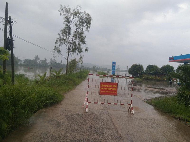Lực lượng chức năng cắm biển báo không cho người và phương tiện qua lại trên các tuyến giao thông bị ngập ở huyện Đồng Xuân.
