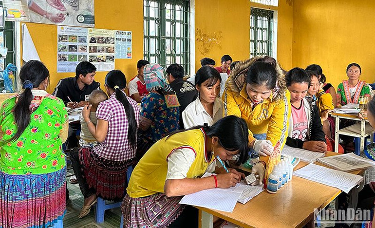 Giảng viên hướng dẫn học viên lớp đào tạo nghề tại bản Hua Huổi Luông cách ghi chép lịch tiêm phòng bệnh cho vật nuôi.