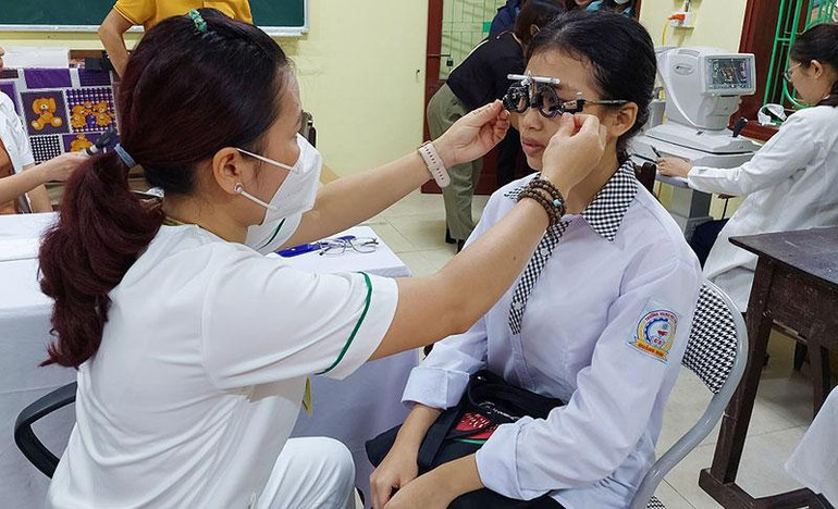 Các y, bác sĩ khám mắt cho học sinh.