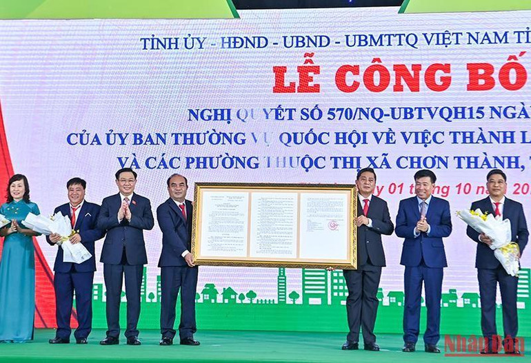 Chủ tịch Quốc hội Vương Đình Huệ trao Nghị quyết của Ủy ban Thường vụ Quốc hội cho lãnh đạo thị xã Chơn Thành. (Ảnh: Duy Linh)