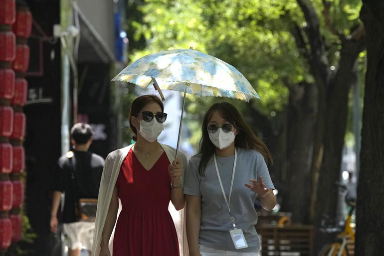 Người dân che ô đi bộ dưới hàng cây. (Ảnh: AP)