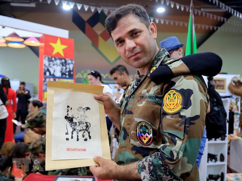 Sỹ quan Ibrahim Homidi vui mừng khi được tìm hiểu về dòng tranh dân gian Đông Hồ trên giấy gió và tự tay hoàn thiện tác phẩm đầu tay của mình. (Ảnh: Trần Hiếu/TTXVN)