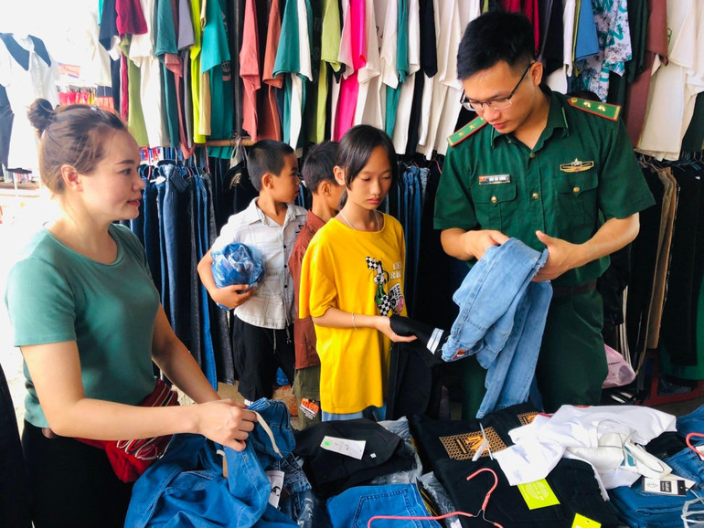 Cán bộ, chiến sĩ Đồn Biên phòng Thị Hoa đưa các cháu đi chọn mua quần áo mới.