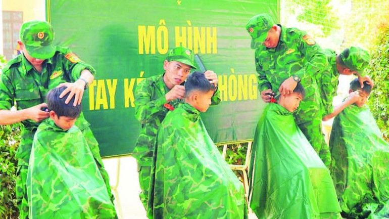 Các chiến sĩ Bộ đội Biên phòng cắt tóc cho học sinh Trường tiểu học Bế Văn Đàn, xã Pờ Y, huyện Ngọc Hồi.