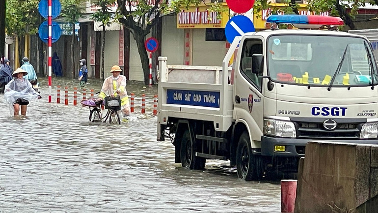 Một chiến sĩ dắt xe cho người dân tại điểm ngập chân cầu Đò Quan, thành phố Nam Định.