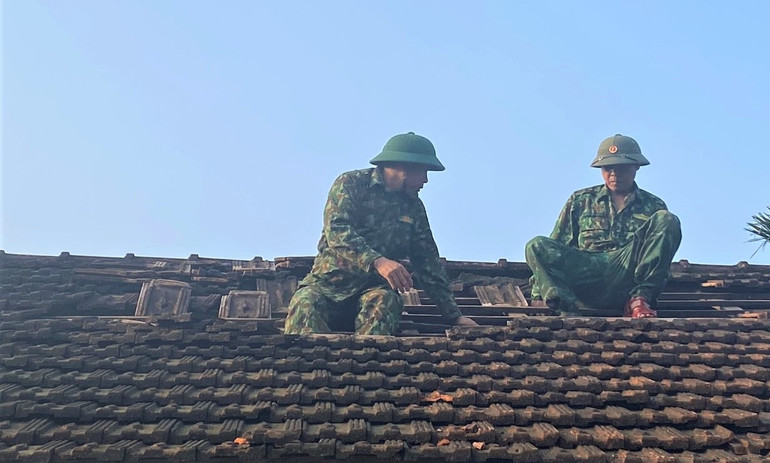 Cán bộ, chiến sĩ Đồn Biên phòng Phúc Sơn giúp người dân lợp lại mái nhà bị hư hỏng.
