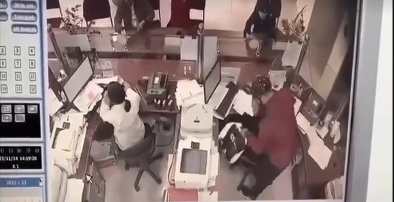 Đối tượng Nguyễn Tuấn Anh (mặc áo đỏ, bên phải ảnh) đang khống chế nhân viên ngân hàng. (Ảnh cắt từ video clip)