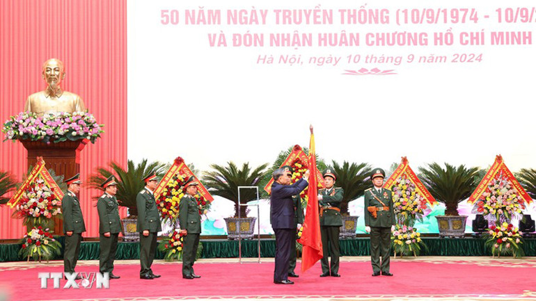 Tổng Bí thư, Chủ tịch nước Tô Lâm gắn Huân chương Hồ Chí Minh lên lá cờ truyền thống của Tổng cục Kỹ thuật (Ảnh: TTXVN)