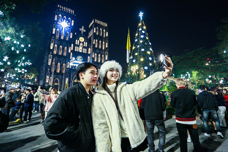 Các bạn trẻ chụp ảnh lưu niệm tại khu vực Nhà thờ lớn tại Hà Nội trong đêm Giáng sinh. (Ảnh: QUỐC TOẢN)