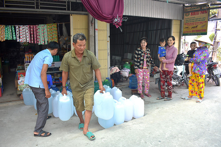 Người dân xã Biển Bạch (huyện Thới Bình, tỉnh Cà Mau) tiếp nhận nước uống miễn phí từ nhà hảo tâm để giải cơn khát.