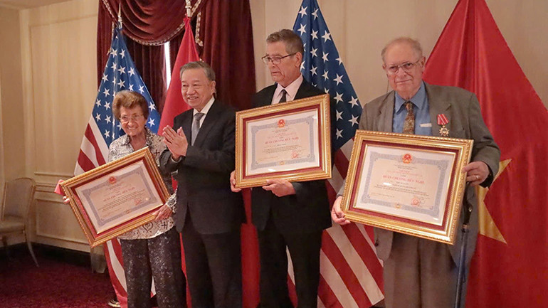 Ông John McAuliff (phải), nhà thơ Bruce Weigl (đứng giữa) và bà Cora Weiss (trái) nhận Huân chương Hữu nghị.