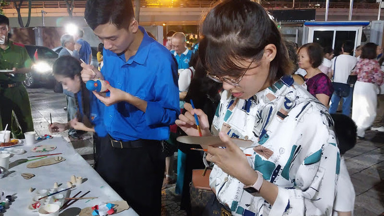 Khách mời trực tiếp trang trí búp bê Nga và tô màu tranh đĩa bằng gỗ.