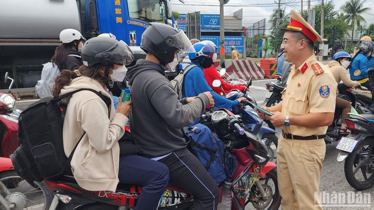 Cảnh sát giao thông phát tờ rơi cho người dân trên đường về quê.