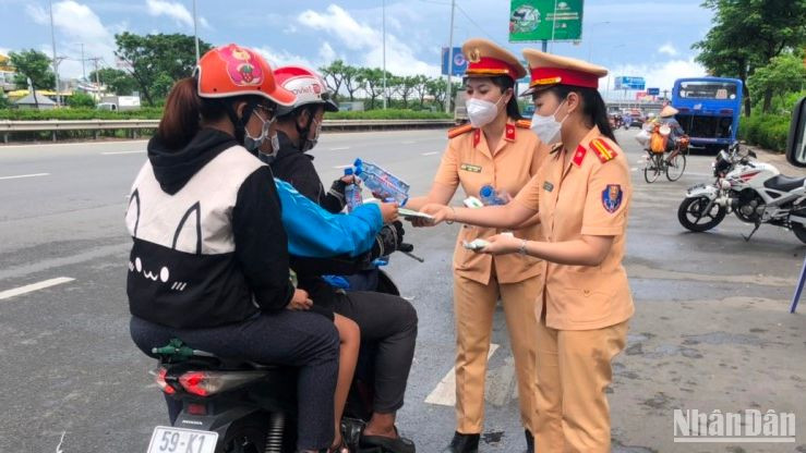 Các nữ cảnh sát giao thông phát nước cho người dân đi đường.