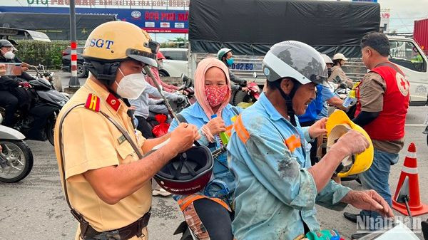 Một cán bộ Cảnh sát giao thông sửa mũ bảo hiểm cho người dân trên đường về quê nghỉ Lễ 2/9.