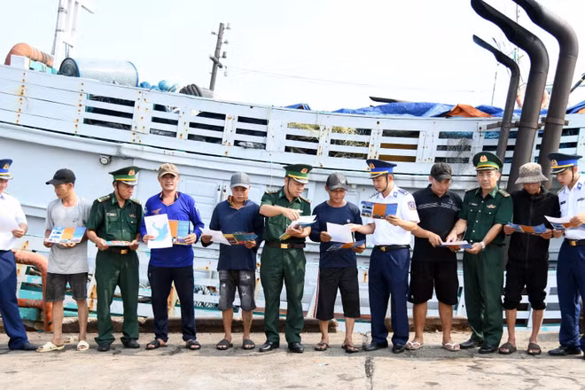 Bộ đội biên phòng Thành phố Hồ Chí Minh và Cảnh sát biển 3 phát tờ rơi tuyên truyền phòng chống IUU tại cảng cá Cát Lở. (Ảnh: Cảnh sát biển cung cấp) 