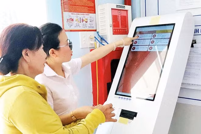 Cán bộ Trung tâm Phục vụ hành chính công xã Hòa Phú hướng dẫn người dân lấy số xếp hàng tự động.