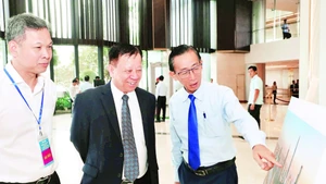 Các đại biểu tham quan triển lãm ảnh mô phỏng Trung tâm Tài chính quốc tế tại Thành phố Hồ Chí Minh. (Ảnh HOÀNG TRIỀU)