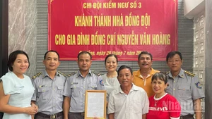 Đồng chí Vũ Văn Tài, Bí thư Đảng ủy Chi đội Kiểm ngư số 3 (thứ hai từ trái sang) trao kinh phí hỗ trợ nhà đồng đội cho gia đình đồng chí Nguyễn Văn Hoàng. (Ảnh: TIẾN DŨNG)