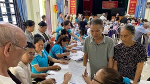 Hội Phụ nữ xã Ô Diên hướng dẫn người dân khai hồ sơ trợ cấp bảo hiểm xã hội. (Ảnh: DIỆU THƯƠNG)