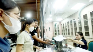 Người dân nộp tiền khám sức khỏe tại Bệnh viện Bạch Mai, Hà Nội. (Ảnh NGUYỄN KHÁNH)