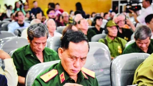 Thiếu tướng Trịnh Xuân Chuyền đọc những dòng chữ trong hồ sơ của đồng đội được trao trả. (Ảnh GIA KHÁNH)