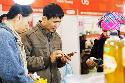 Người dân dùng điện thoại để truy xuất thông tin các sản phẩm nông sản. Ảnh: NAM ANH