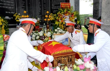 Các cựu chiến binh xã Thông Tân thực hiện nghi thức phủ Quân kỳ cho liệt sĩ Ngô Đức Mai. (Ảnh: THÀNH CHUNG)