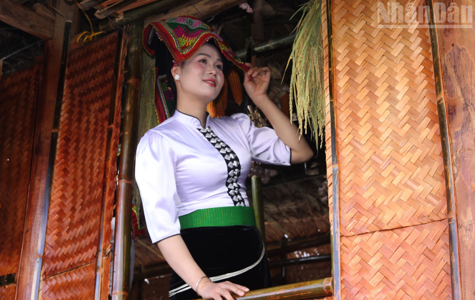 Ca Thi Xom ក្នុងសំលៀកបំពាក់ជនជាតិថៃខ្មៅឈរលើរានហាលនៃផ្ទះឈើដែលបង្ហាញពីលំហវប្បធម៌របស់ជនជាតិឡាវ-ខ្មែរ។ ndo_tr_11.jpg