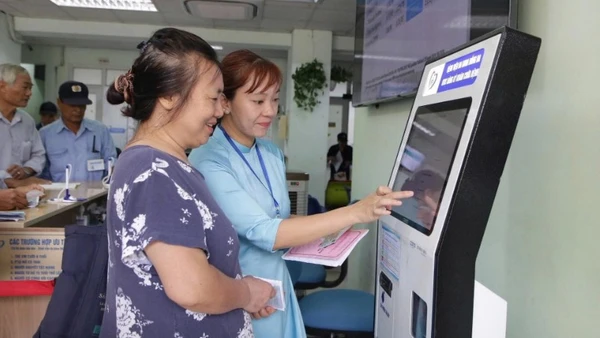 Cán bộ Bệnh viện Đống Đa (Hà Nội) hướng dẫn người dân sử dụng công nghệ số trong việc đăng ký khám, chữa bệnh. (Ảnh HUY HOÀNG)