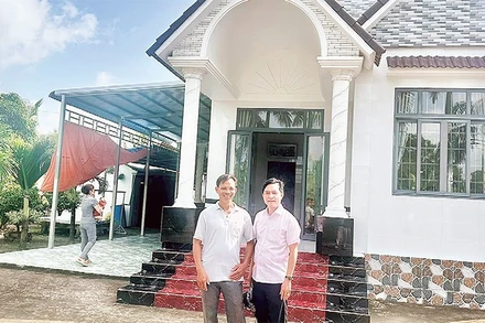 Nông dân Trần Quốc Thống (bên trái) trồng lúa ST 25 kết hợp nuôi tôm, mỗi năm thu lãi hơn một tỷ đồng, vừa xây nhà mới khang trang.