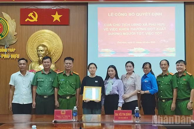 Bà Võ Thị Bình, Chủ tịch Ủy ban nhân dân xã Phú Hựu, tỉnh Đồng Tháp, (đứng thứ 5 từ phải qua trái) trao khen thưởng đột xuất cho em Phạm Nguyễn Anh Thư.