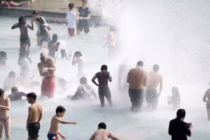 Người dân tránh nóng tại đài phun nước ở Paris, Pháp. Ảnh: THX/TTXVN