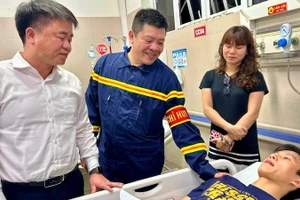 Đại diện Đảng ủy, Ủy ban nhân dân phường Hoàng Mai thăm hỏi, động viên anh Nguyễn Lê Tú, người tham gia giải cứu các nạn nhân vụ cháy tại đường Lĩnh Nam. (Ảnh: Trần Oanh)