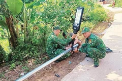 Cán bộ, chiến sĩ Đồn Biên phòng Bắc Xa lắp cột đèn năng lượng tại thôn Bản Hang, xã Kiên Mộc.