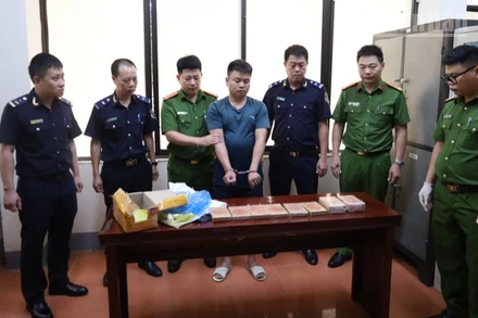 Các lực lượng chức năng bắt giữ đối tượng Hoàng Văn Cường cùng tang vật là 10 bánh heroin.